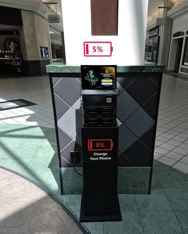 Charging kiosk with a screen in a shopping mall walkway