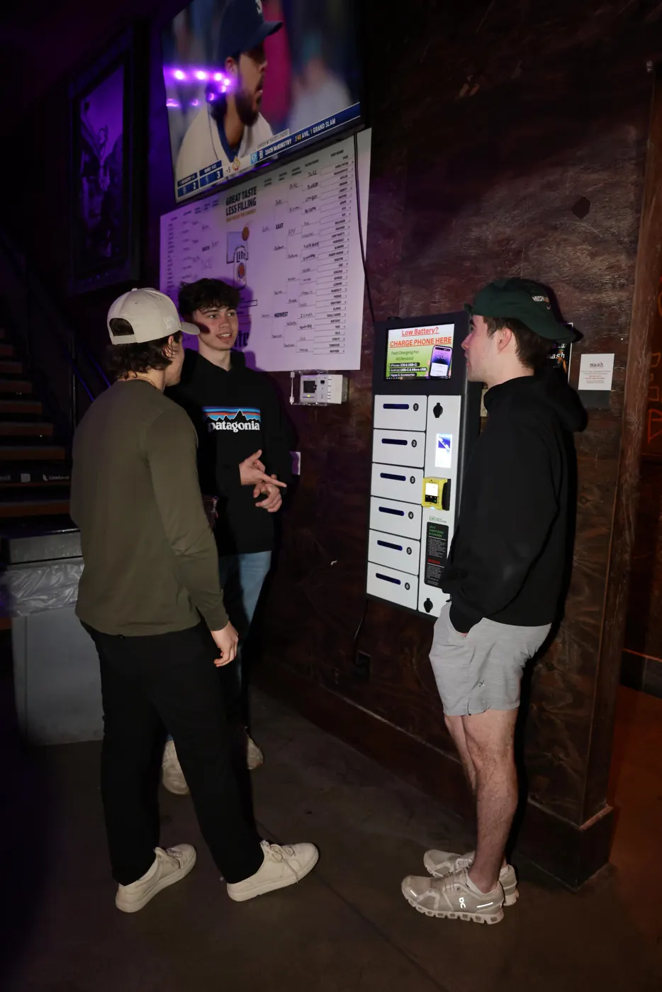 Students standing next to a charging locker in a sports bar
